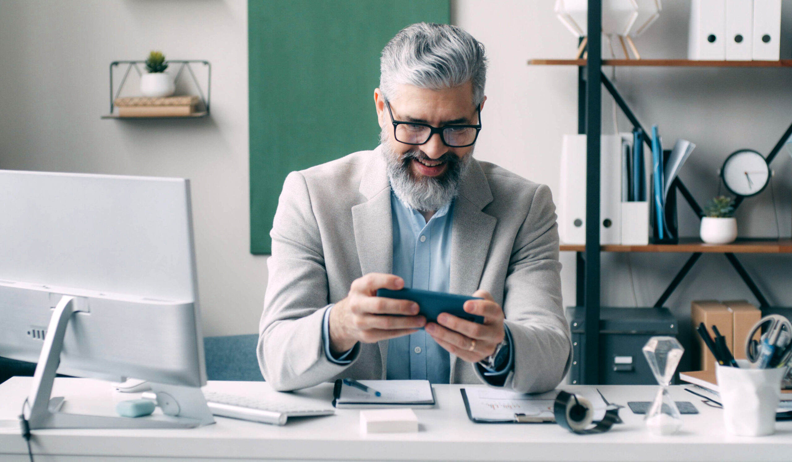 Mitarbeiter am Schreibtisch mit Monitor und Handy